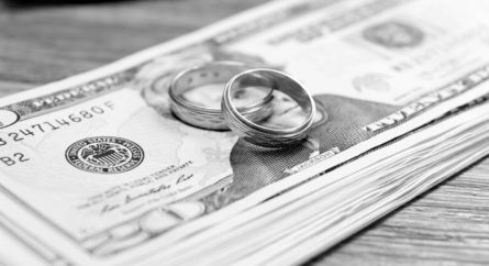 Two wedding bands sitting on a stack of money