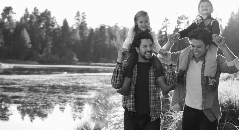 Gay Male Couple With Children Walking By Lake