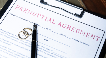 Close Up Of A Prenuptial Agreement Form With Wedding Rings And A Fountain Pen, Indicating The Legal Aspects Of Marriage Preparation.