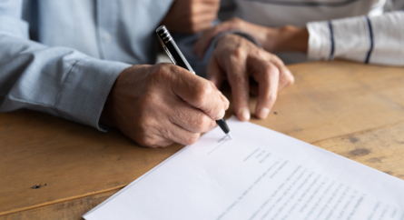 Close Up Older Man Putting Signature On Legal Documents