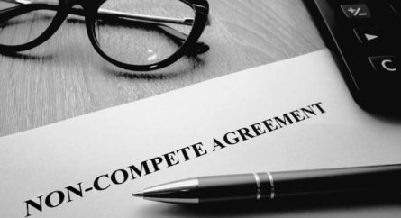 Noncompete agreement on a desk with a pen and a pair of glasses