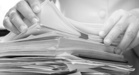 Business person leafing through stacks of paperwork